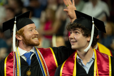 Two students in graduation regalia at 2024 Undergraduate Commencement